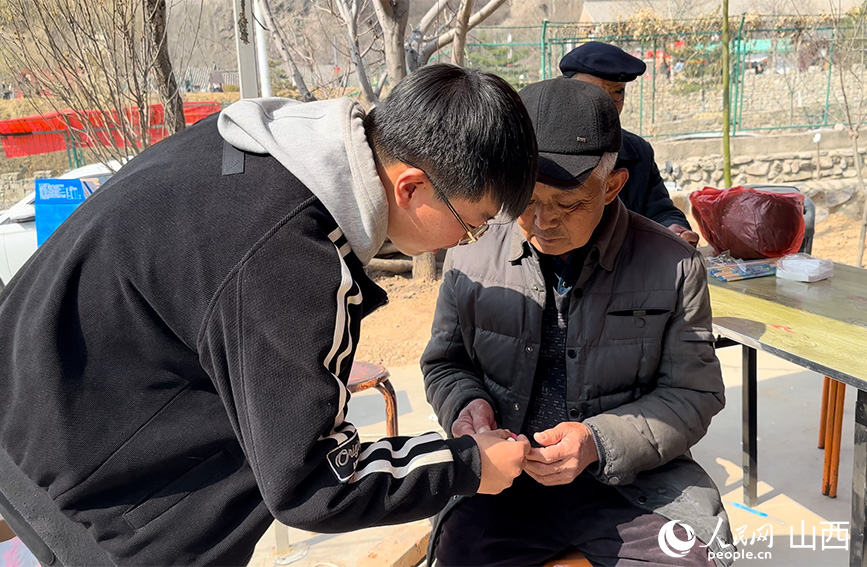 何國賓為老人發放愛心卡片。人民網 董童攝