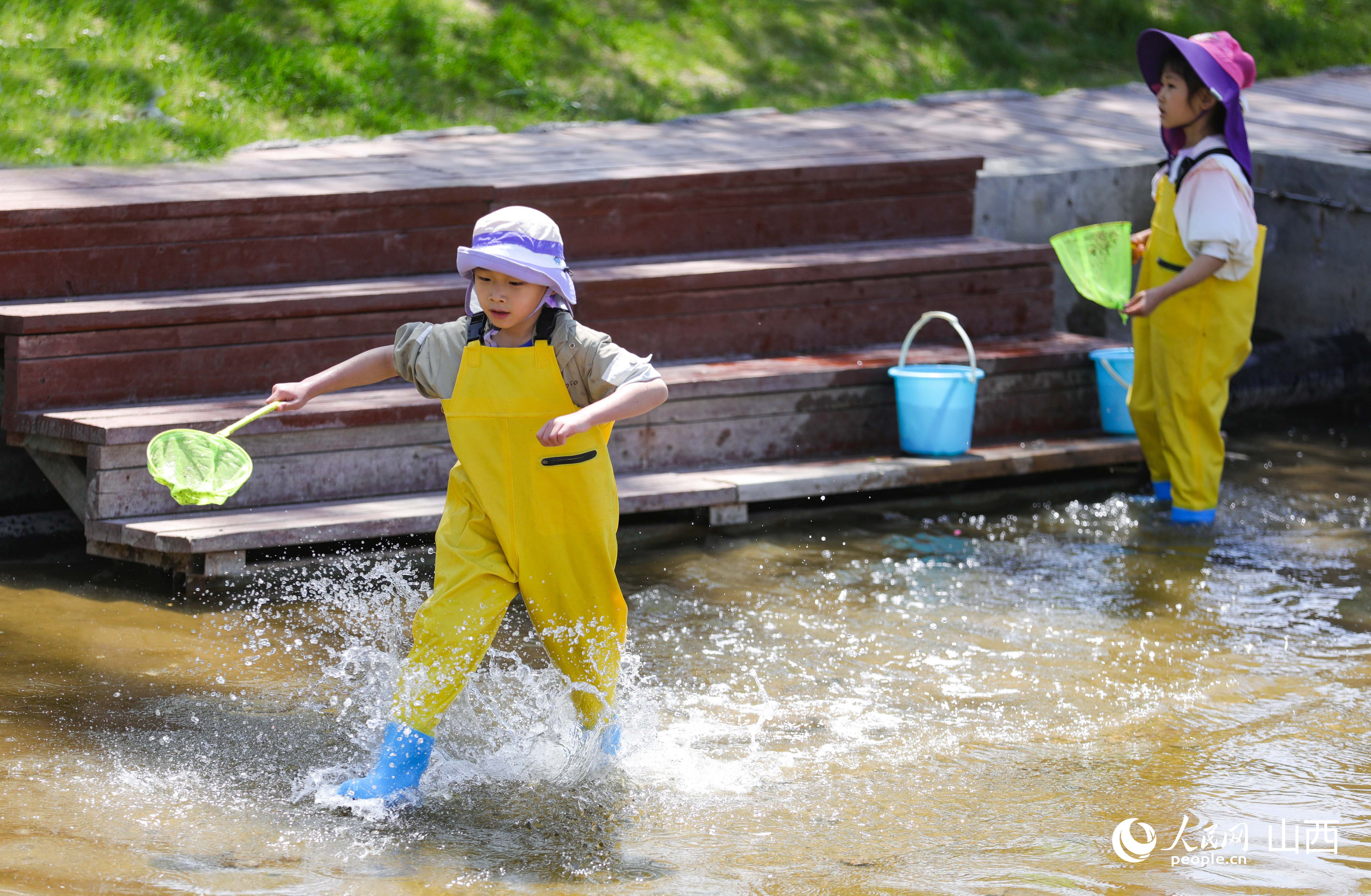 孩子們穿戴防水服在池塘玩耍。