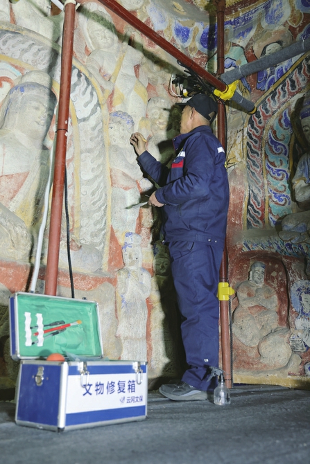 文物修復人員正在修復佛像。云岡石窟景區供圖